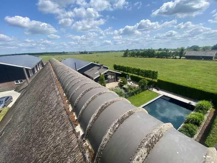 Buitenrenovatie van een rietgedekte woning met donkere gevelbetimmering